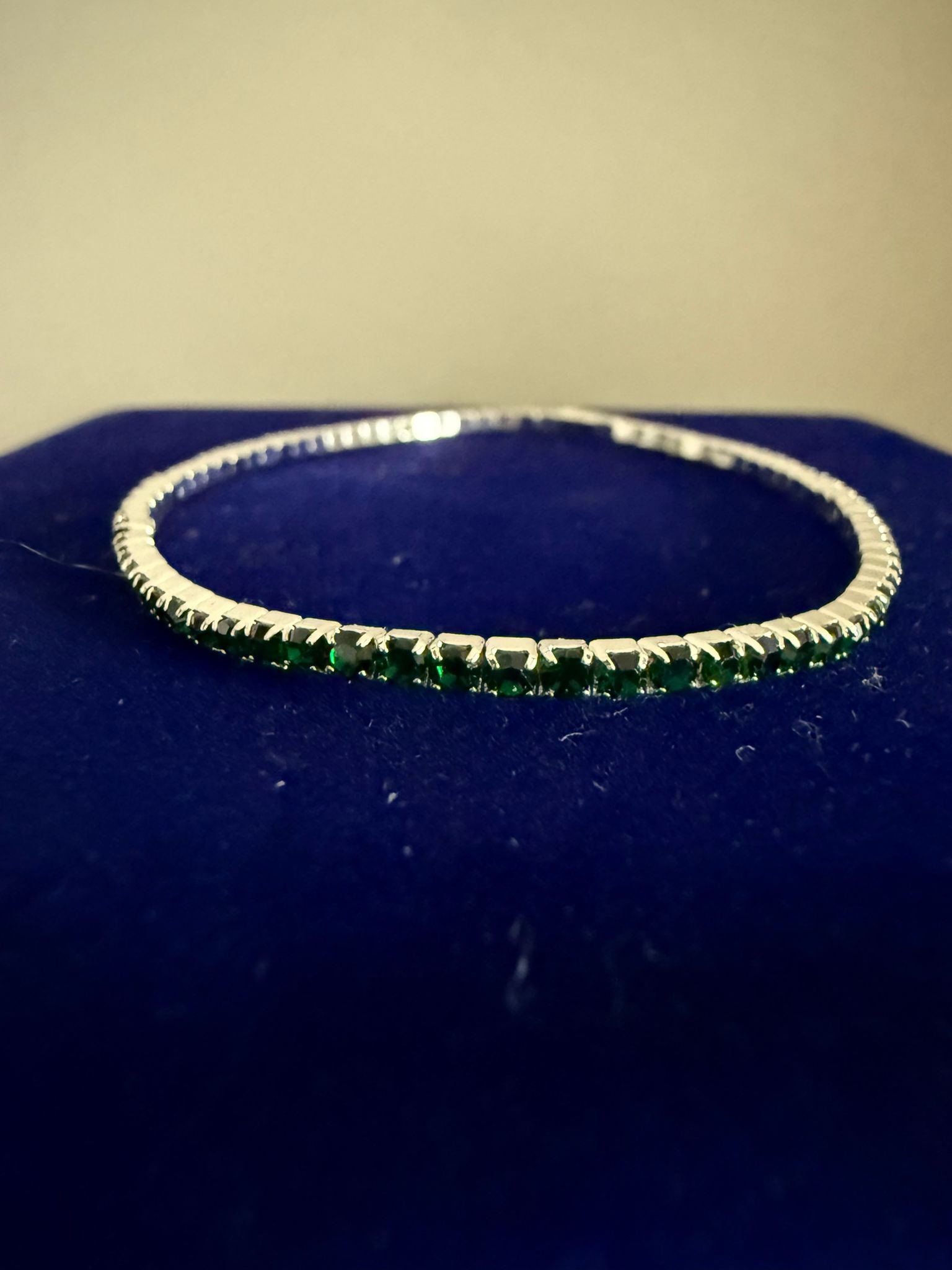 Elegant elastiskt tennisarmband i guldfärgad stål och grön emerald sten