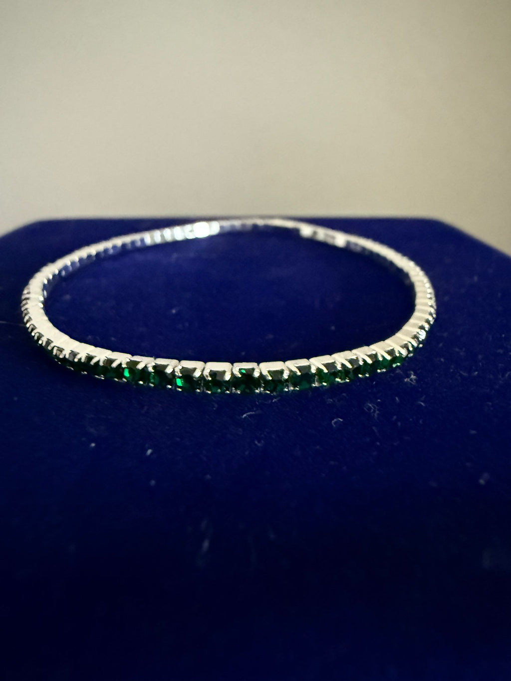 Elegant elastiskt tennisarmband i guldfärgad stål och grön emerald sten