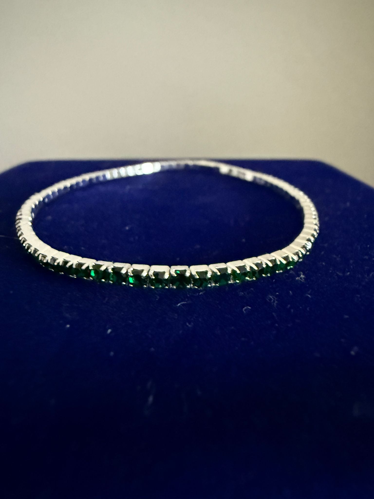 Elegant elastiskt tennisarmband i guldfärgad stål och grön emerald sten